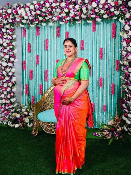 Advithi looks absolutely splendid in a vibrant pink and orange saree with a contrasting green blouse for her baby shower. The colors are a celebration of life and joy.