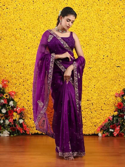 The graceful drape of the purple organza saree is captured in this elegant shot.