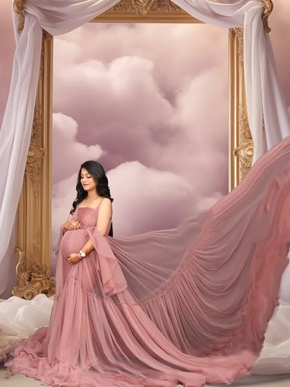 A dreamy, heavenly portrait of a mom-to-be in a pink gown, standing among clouds with a golden frame behind her. The flowing fabric and soft colors create a truly magical scene.