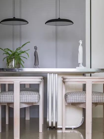 The dining area, with its marble-topped table and modern chairs, is set against a grey-toned backdrop with intricate detailing, creating a look of understated elegance.