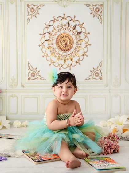A happy, clapping little girl, enjoying her storybook time in a beautiful, classic studio setting.