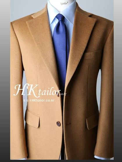 A classic camel colored blazer on a mannequin, showcasing the sharp cut and notched lapels. This is a versatile piece that can be paired with formal trousers or jeans.
