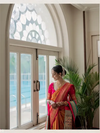 A quiet, contemplative moment captured by the window. This shot showcases the bride's elegant profile and the beautiful stained-glass detail of the window, adding an architectural element to the portrait.