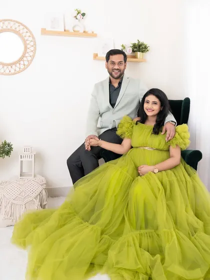 A lovely portrait of an expecting couple in our studio. The mother-to-be is radiant in a flowing green gown, holding hands with her partner.