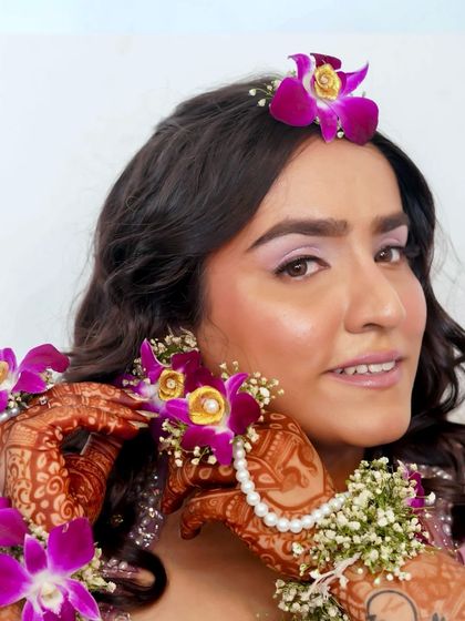 A beautiful look for a Haldi or Mehendi ceremony. The makeup is subtle and elegant, with a focus on natural radiance to complement the floral jewelry.