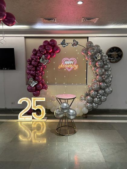 A beautiful 25th-anniversary ring in magenta and silver, decorated with butterfly accents and a "Happy Anniversary" neon sign.