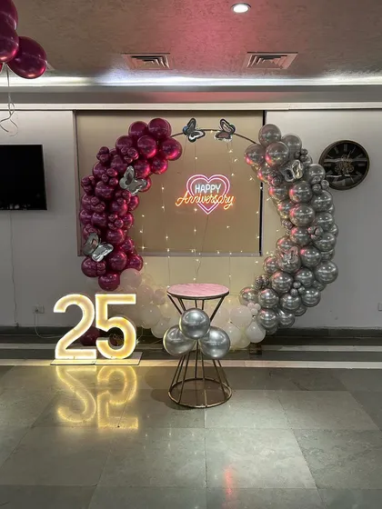 A beautiful 25th-anniversary ring in magenta and silver, decorated with butterfly accents and a "Happy Anniversary" neon sign.