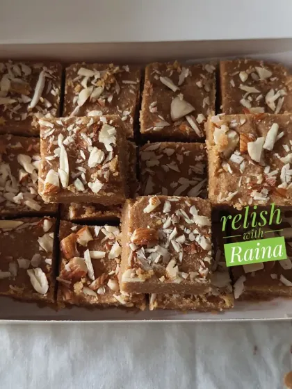 A box of Gur Padi or Sukhdi, a classic Gujarati sweet. Made with whole wheat flour, pure ghee, and jaggery, it has a delightful crispy texture and is topped with sliced almonds.