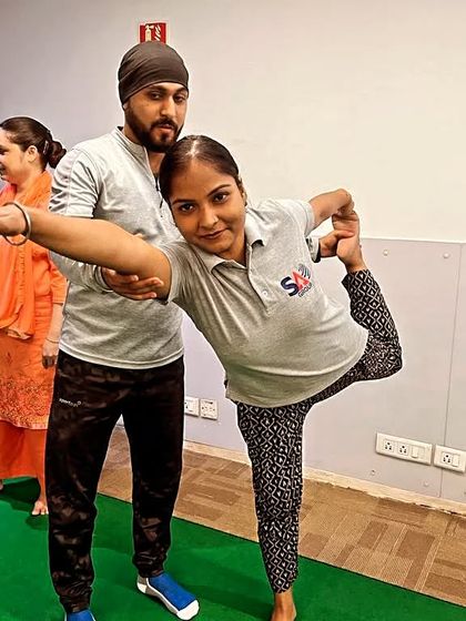 Providing a personal adjustment to an employee during a corporate yoga session. I ensure everyone feels comfortable and practices safely, even in a group setting.