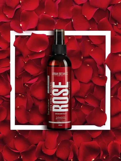 A striking flat lay of Urban Botanics rose water, framed by a bed of fresh red rose petals. This top-down composition is highly effective for e-commerce and social media, creating a clean yet visually rich product image.