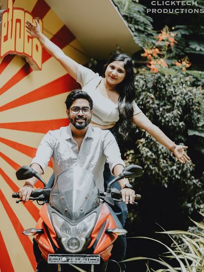 A fun and energetic shot of a couple on a motorcycle, with a retro-themed backdrop, capturing their adventurous spirit.