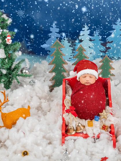 A festive newborn portrait for the holidays. This little one is nestled in a tiny sleigh, dressed in a Santa-inspired wrap, creating a perfect first Christmas memory.