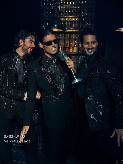 This is the energy of the 'Late Check Out' collection. Three men, each in a distinct black-on-black sequined jacket, command the room. It shows the variety within a single theme, from subtle shimmer to bold patterns.