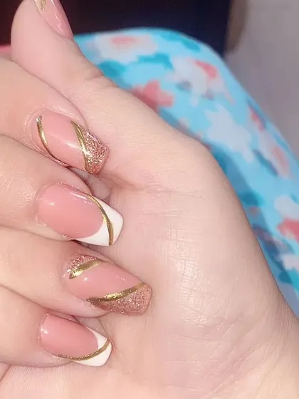 A creative manicure combining a classic white French tip with an accent nail featuring a gold glitter and pink design.
