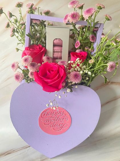 A heart-shaped floral box created for Mother's Day. This unique packaging combines a beautiful flower arrangement with a box of delicate macarons.