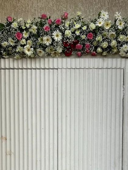 A close-up of the floral work on the entrance arch. We used a beautiful mix of fresh pink roses, white gerbera daisies, and baby's breath for a full and luxurious look.