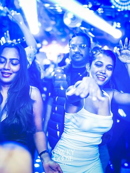 A close-up of partygoers dancing under the cool blue lights.