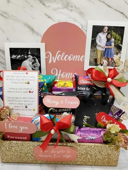 A 'Welcome Home' kit for a recently engaged couple. This glittery gold tray is filled with their favorite snacks, personalized photo frames, and cute message cards.