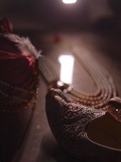An artistic composition of the groom's accessories: his turban, necklace, and shoes.