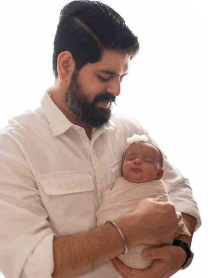 The sweet, sleepy smile of a newborn held securely in her father's arms. Capturing these fleeting expressions is a joy.
