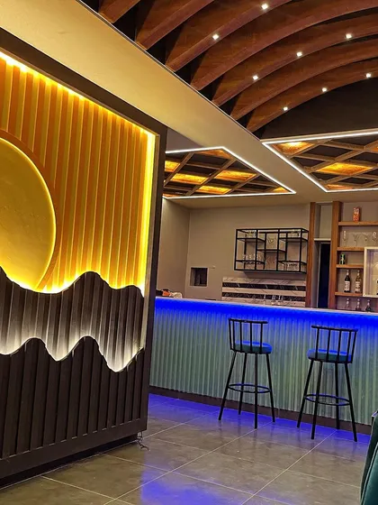 A closer look at our newly designed bar area with cool blue ambient lighting. It's a great spot to pull up a stool and enjoy a drink, highlighting the modern and cozy feel of our space.