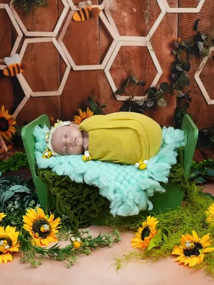 Our sweet little honeybee. This newborn is sleeping soundly in a green basket surrounded by sunflowers and honeycomb details in our bee-themed setup.