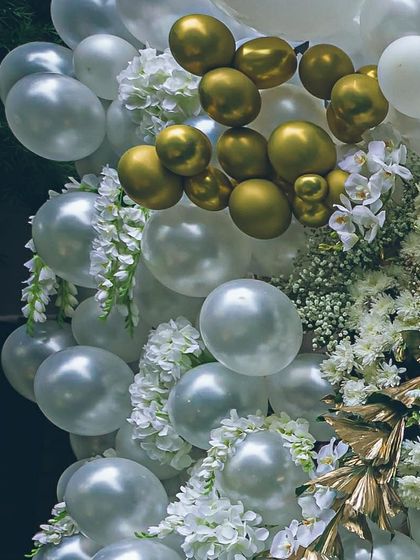 Another angle of the elegant white and gold balloon installation. The interplay of different balloon sizes and the addition of fresh flowers and gold leaf accents create a rich, luxurious texture.