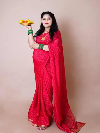 A portrait of a graceful mother-to-be in a vibrant red saree, holding a traditional plate of fruits as an offering.