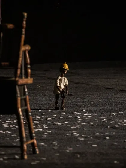 A solitary marionette stands on a stage littered with confetti, creating a poignant and atmospheric image from 'Il Fil'armonico'.