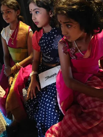 Young actresses waiting backstage, their expressions a mix of anticipation and focus. This candid moment captures the pre-show jitters and excitement.