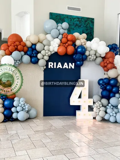 A grand and modern balloon arch for a 4th birthday, using a sophisticated color palette of navy blue, rust, grey, and white.
