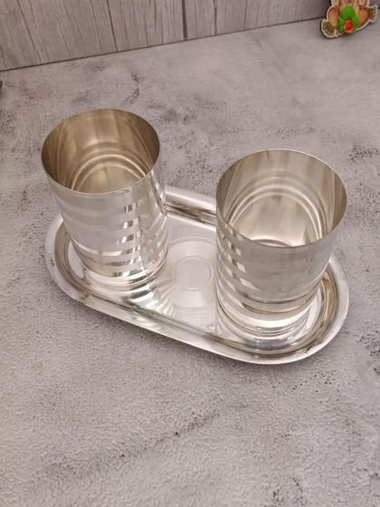 A stainless steel set with two glasses and a matching tray, featuring a silver finish for an elegant look.