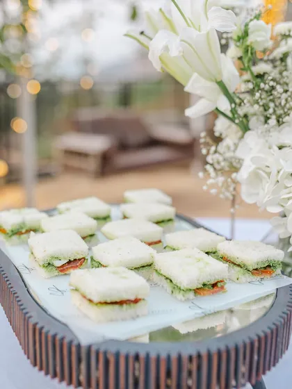 Classic chutney sandwiches, crusts removed, served on a mirrored tray for a cozy high tea at a pre-wedding celebration in Lonavala.