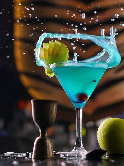 A dynamic splash shot of a blue cocktail, demonstrating the technical skill our commercial photographers use to create eye-catching imagery for bars, restaurants, and beverage brands.