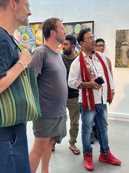 Engaging with international visitors at my art exhibition, explaining the stories behind my paintings.