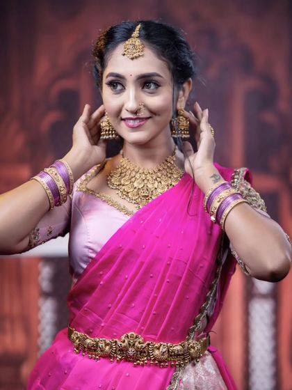 A close-up of the model adjusting her earrings, offering another look at the beautiful jhumkas.