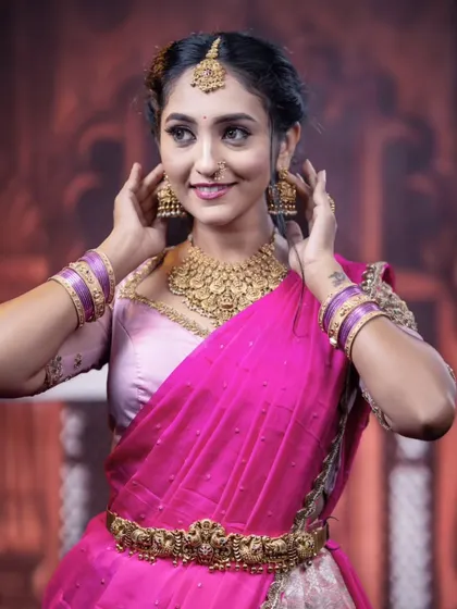 A close-up of the model adjusting her earrings, offering another look at the beautiful jhumkas.