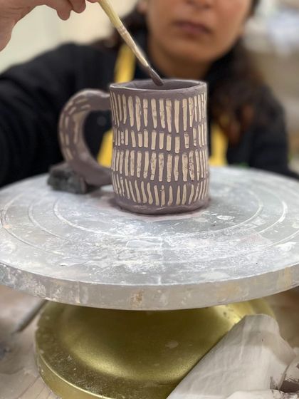 Applying underglaze to a textured mug. The color sinks into the carved lines, which will create a beautiful effect after firing.