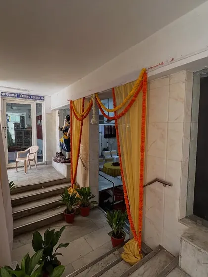 The interior entrance of a venue decorated with yellow drapes and marigold garlands.