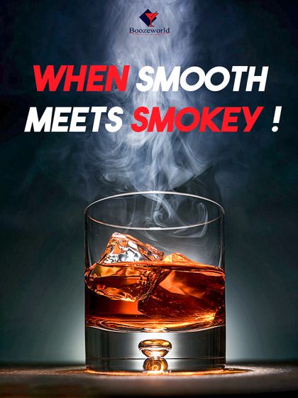 When smooth meets smoky. This image captures the perfect pour of a rich whiskey over ice, with a plume of smoke suggesting a complex, peated flavor profile.