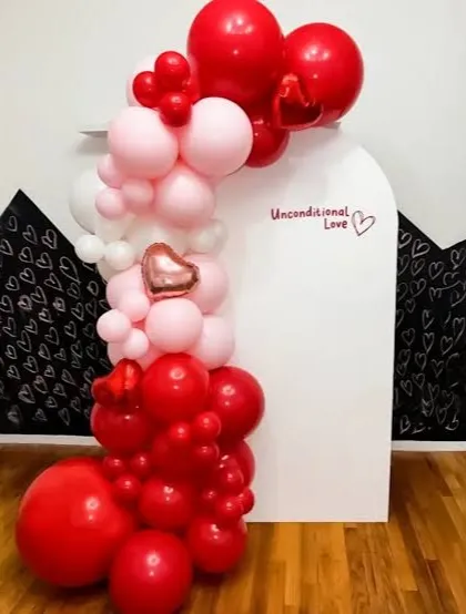 A modern and chic Valentine's decoration featuring a balloon cascade on a white arched panel. The "Unconditional Love" text adds a personal and sweet message to the setup.