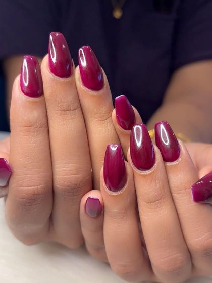 A vibrant cherry red polish on long, coffin-shaped nails.