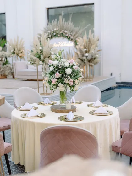 A round table setup for the boho Roka, with a simple floral centerpiece and elegant gold charger plates.