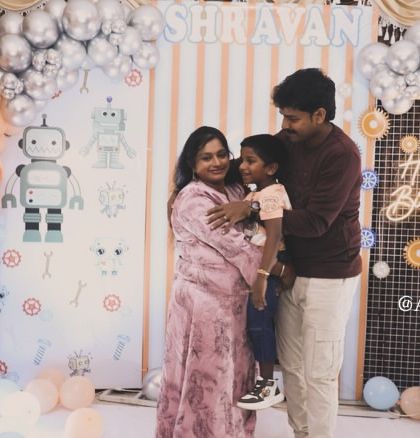 A happy family portrait in front of our custom robot-themed backdrop, complete with a personalized name banner and a 'Happy Birthday' neon sign.