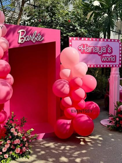 The entrance to 'Hanaya's World', a Barbie-themed party with a pink doorway, balloon arch, and a pink jeep.
