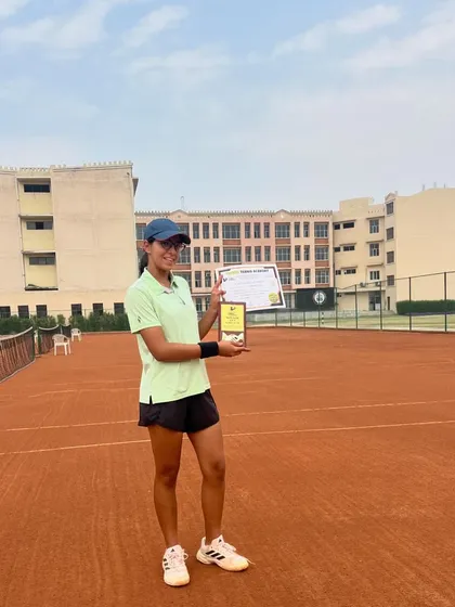 Eshanya Khattar holds her certificate and trophy after winning the AITA CS National U-16 singles tournament in Sonepat. This picture was taken on the clay court, showcasing the venue.