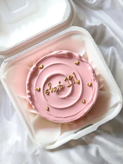 A pretty pink bento cake with "She's 1/1" written in gold, celebrating someone who is truly one of a kind.