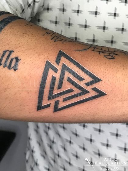 A bold Valknut symbol tattoo on the forearm, a powerful geometric design from Norse mythology.