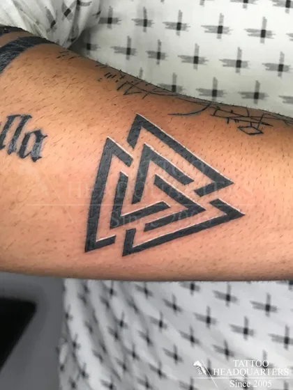 A bold Valknut symbol tattoo on the forearm, a powerful geometric design from Norse mythology.