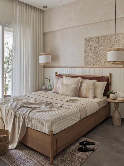 Crafting a haven of tranquility, this master bedroom features a welcoming oak-finished bed with a cozy rust-brown boucle fabric, positioned against a wainscoted wall with ivory and beige textures.